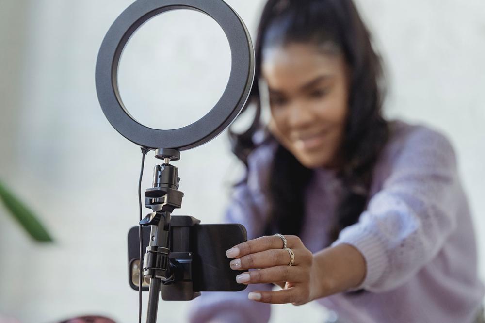 Photo of a young woman setting up a ring light and phone to shoot video
