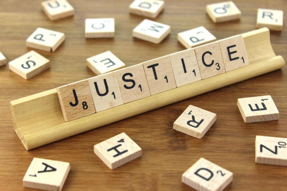 Scrabble tiles spelling out the word justice, surrounded by other tiles